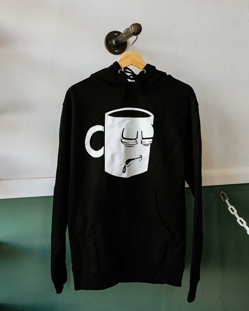 A Tired Eyes Coffee Classic Mug Hoodie with a white print on black hoodie.