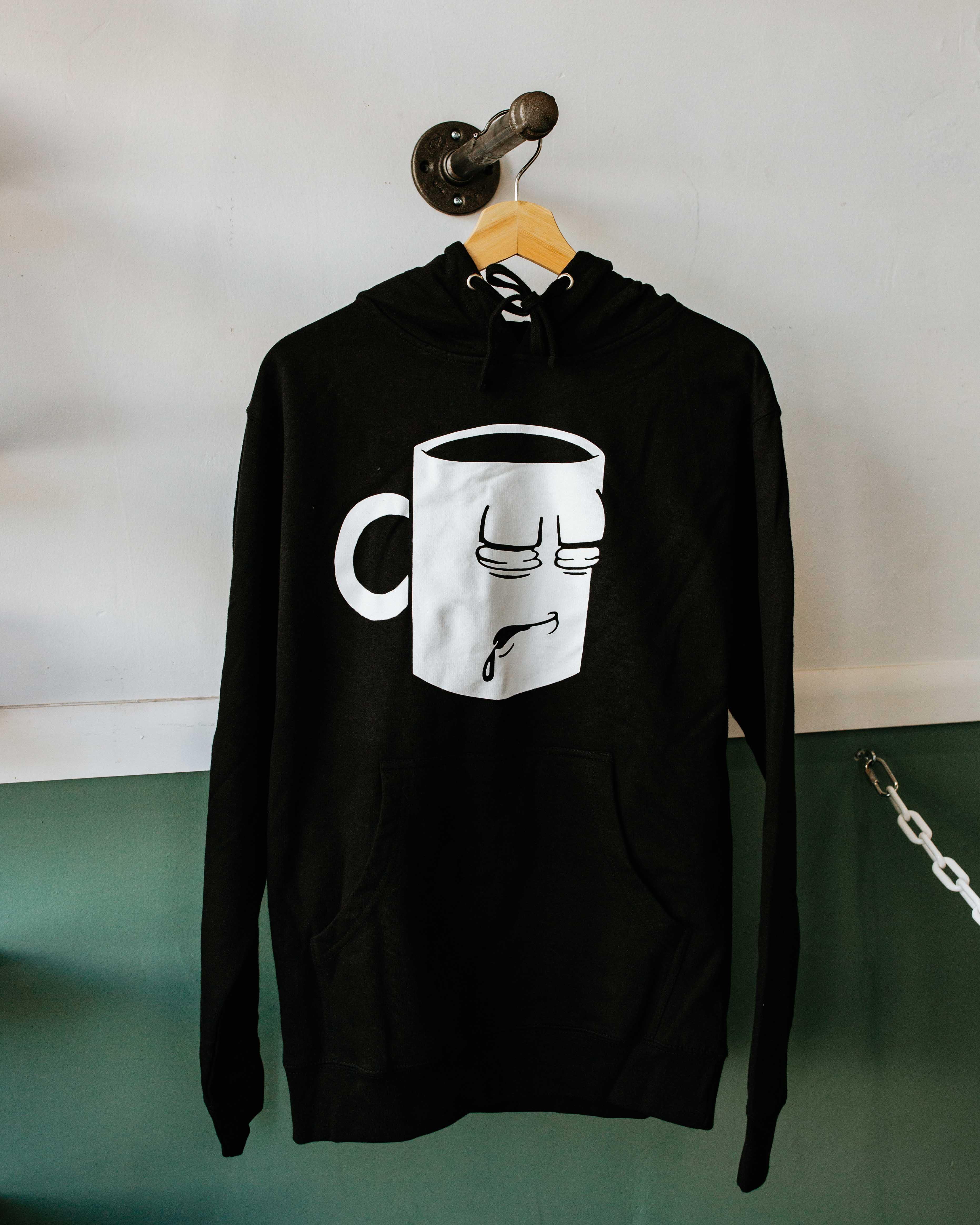 A Tired Eyes Coffee Classic Mug Hoodie with a white print on black hoodie.